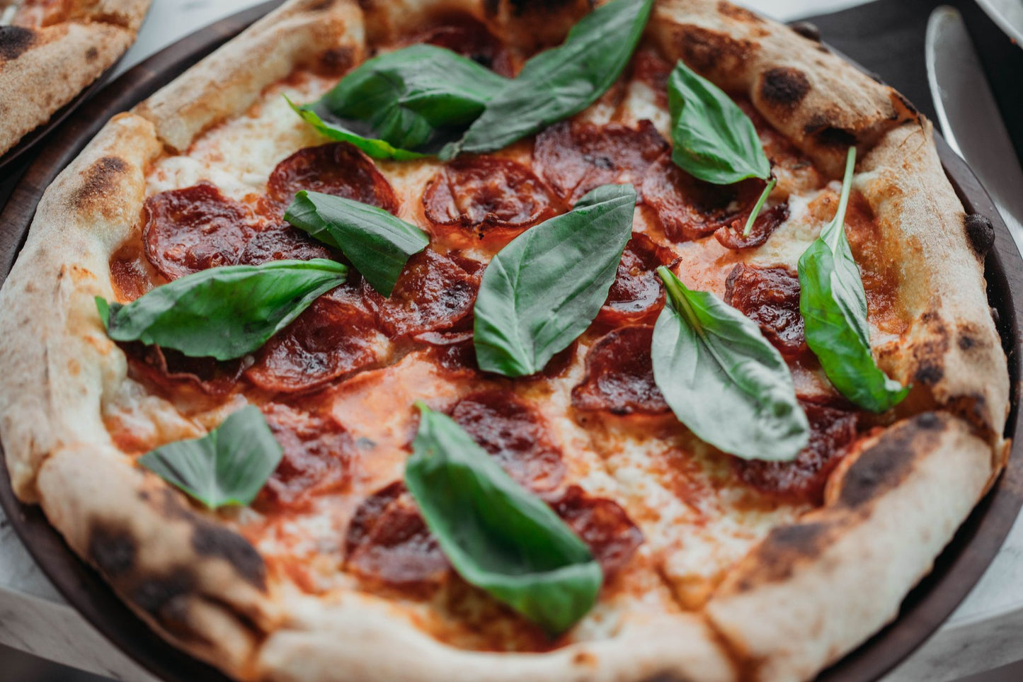 A mouthwatering Italian pepperoni pizza garnished with fresh basil leaves, perfect for a gourmet treat.