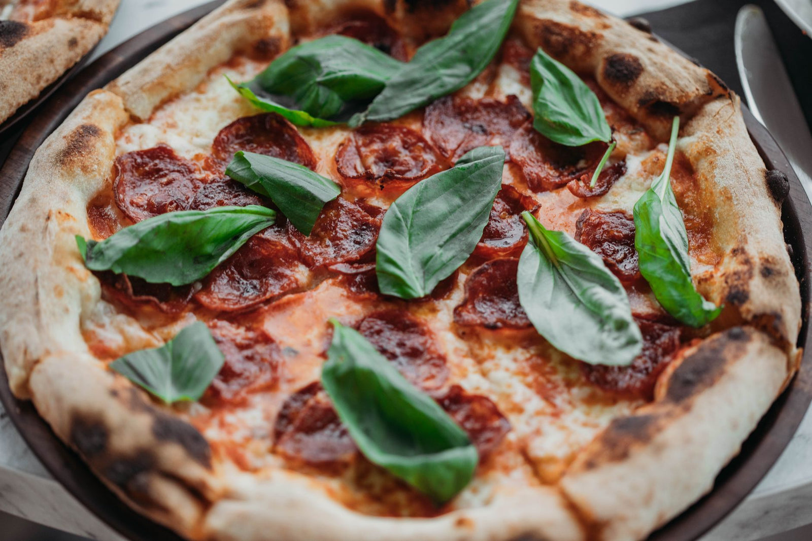 A mouthwatering Italian pepperoni pizza garnished with fresh basil leaves, perfect for a gourmet treat.