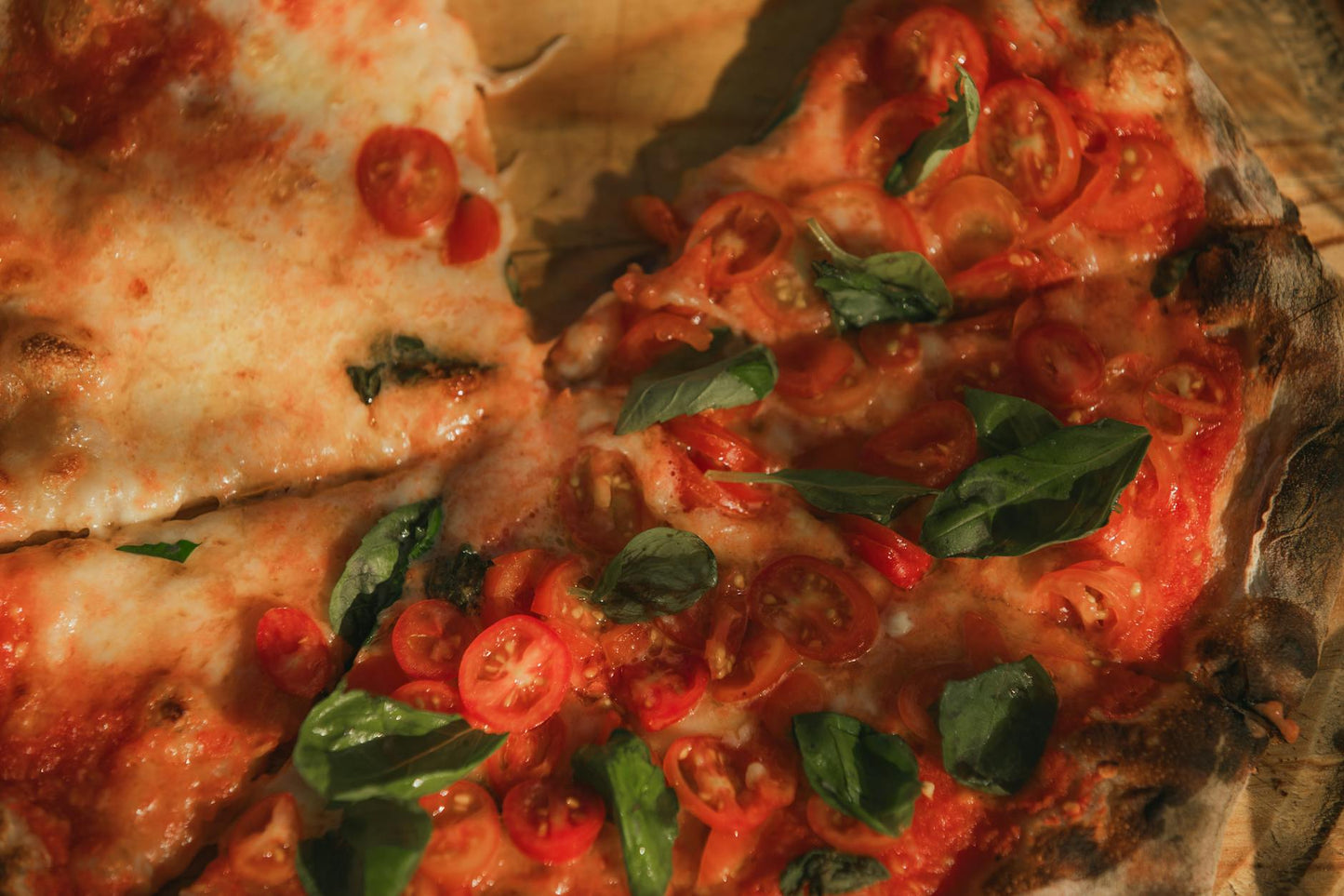 Top view of a baked Margherita pizza with cherry tomatoes, mozzarella, and basil leaves.