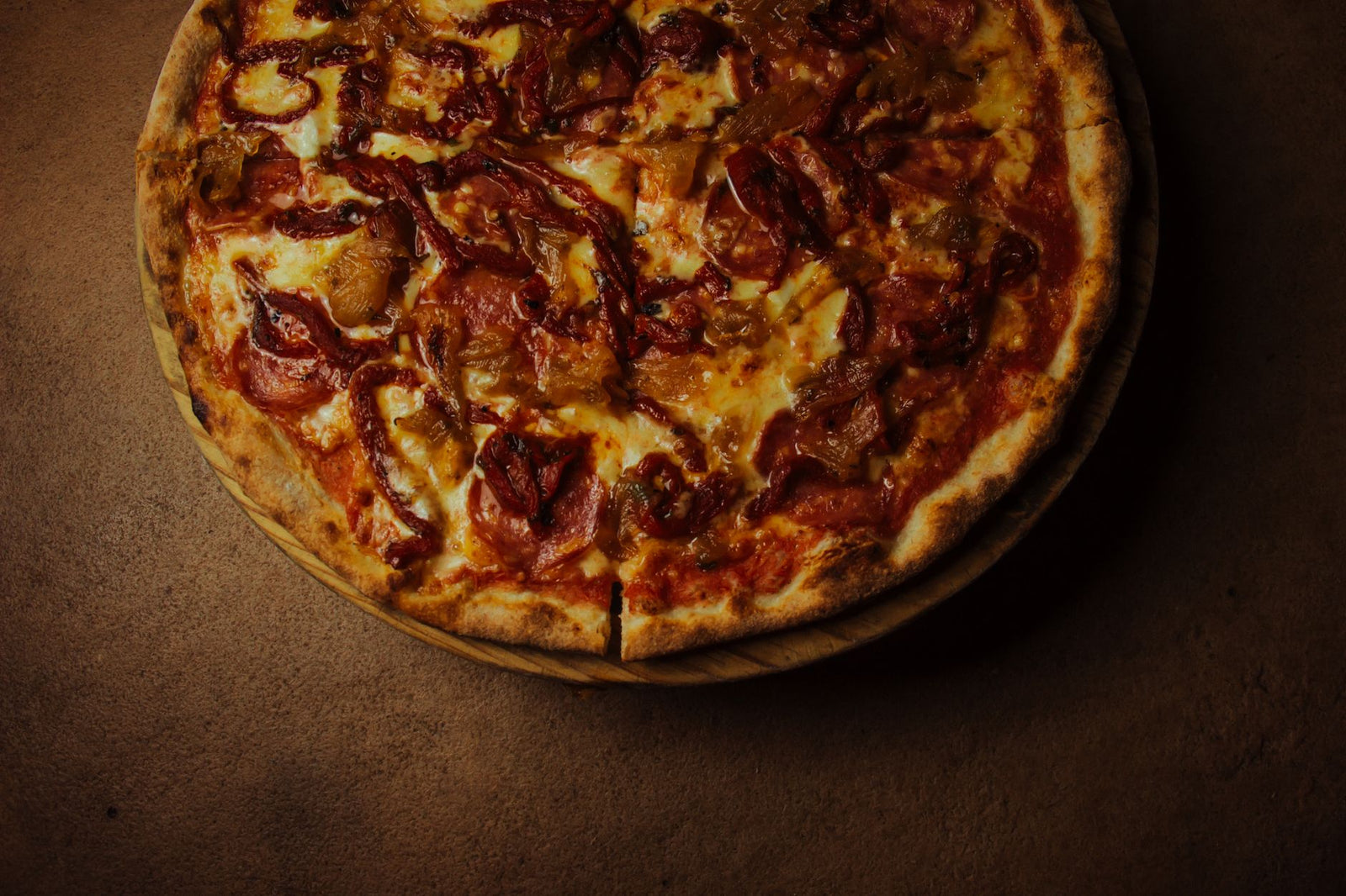 Close-up of a delicious pepperoni pizza on a rustic wooden board, showcasing melted cheese and spices.