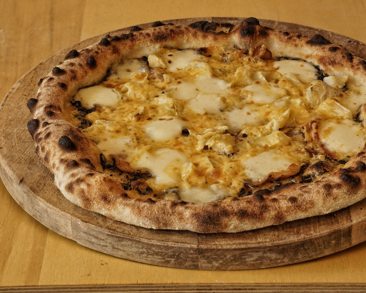 Delicious wood-fired pizza topped with melting cheese on a rustic wooden board.