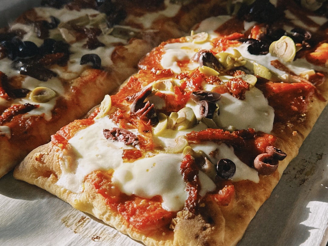 Rectangular pizzas with various toppings including cheese and olives.