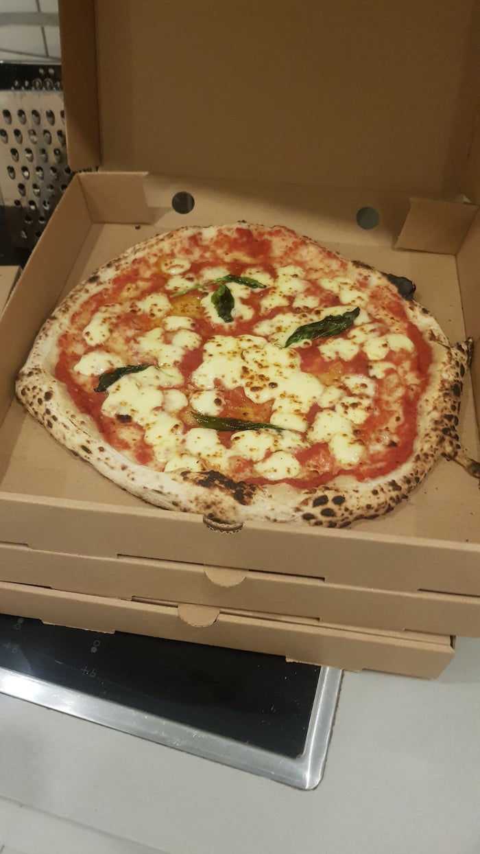 A Margherita boxed up, basil on top