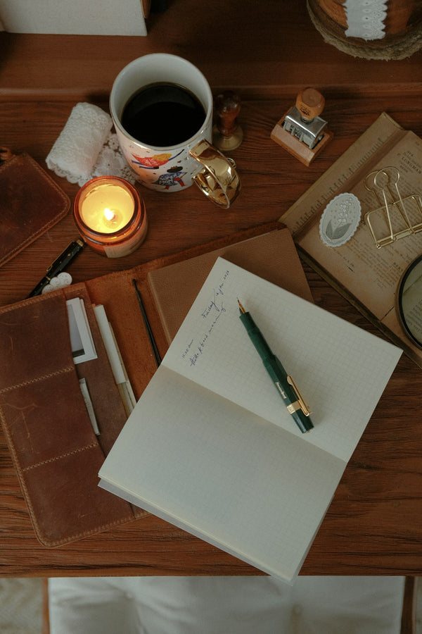 Open notebook and pen on a warm, candlelit desk — The Baker's Journal
