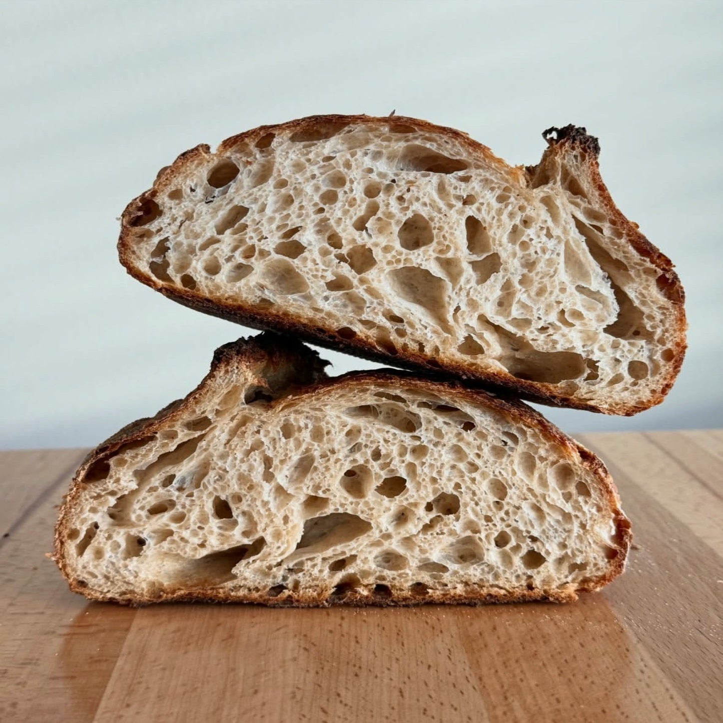 Halved open-crumb sourdough loaf on a wooden board — Sourdough Rescue Handbook