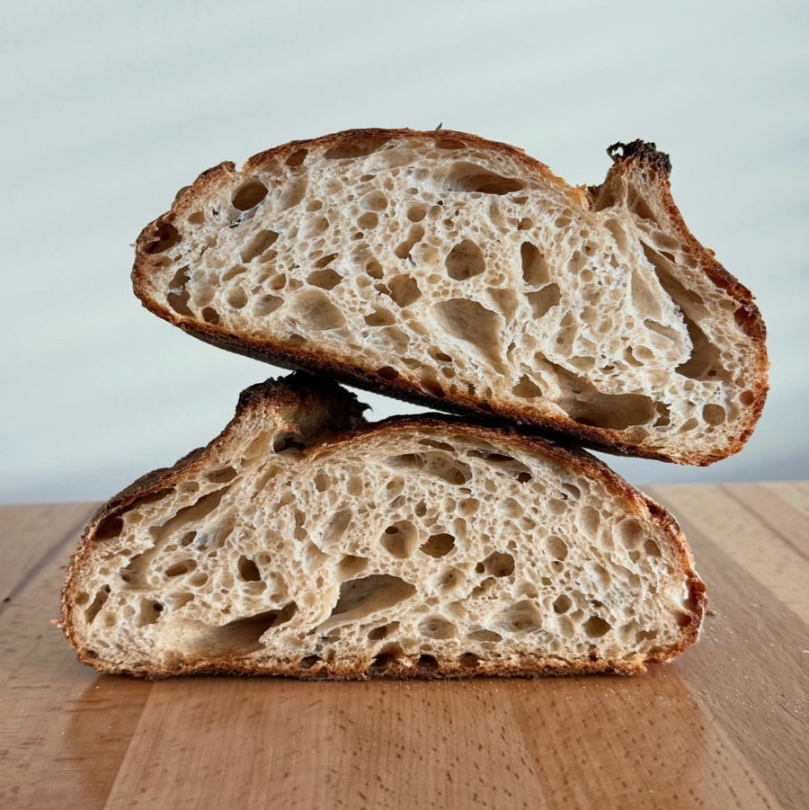 Halved open-crumb sourdough loaf on a wooden board — Sourdough Rescue Handbook