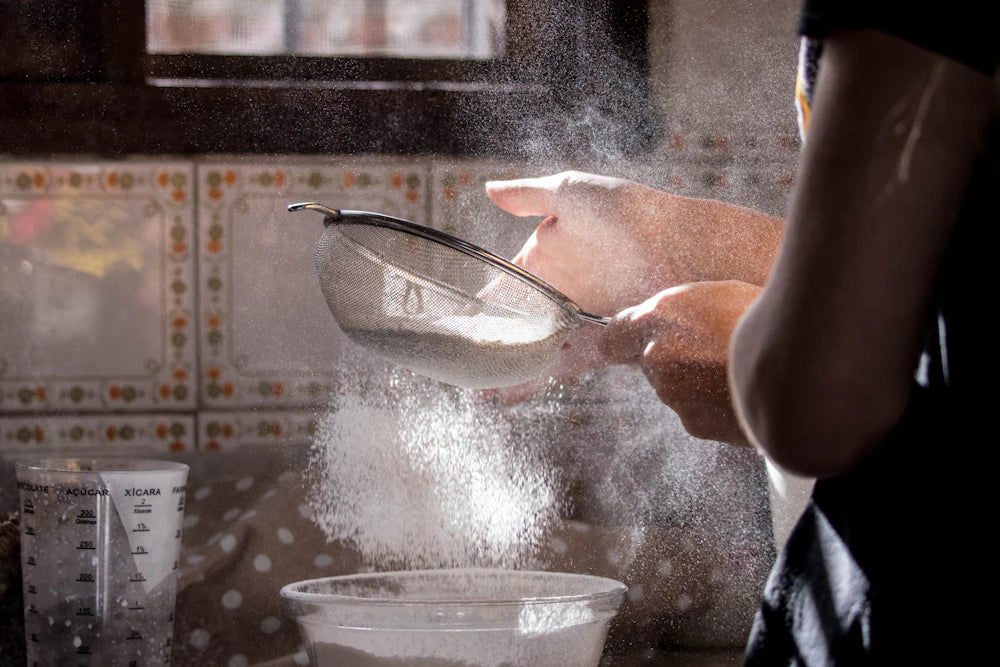 Sifting flour into a bowl to feed a sourdough starter