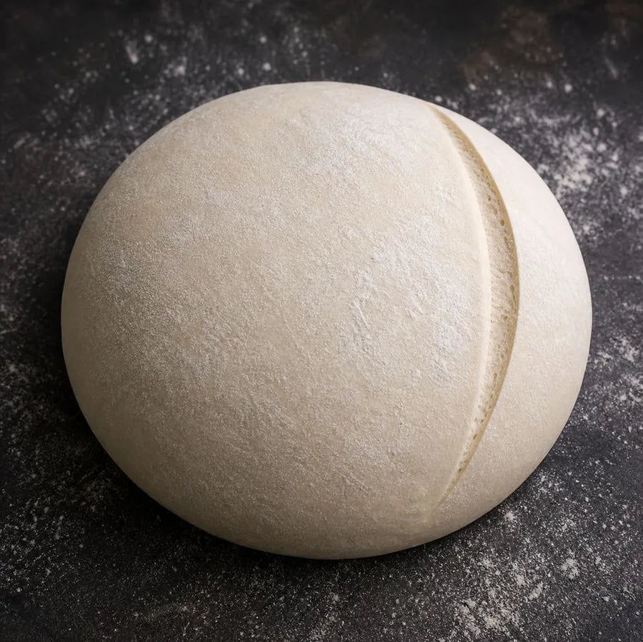 Unbaked sourdough dough scored with a single long slash near the edge